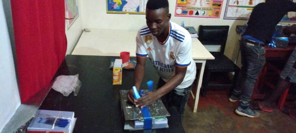 Young man wrapping gift of school supplies