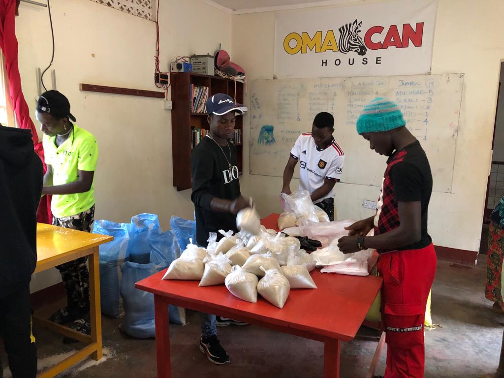 Young men filling grain bags at Omacan House