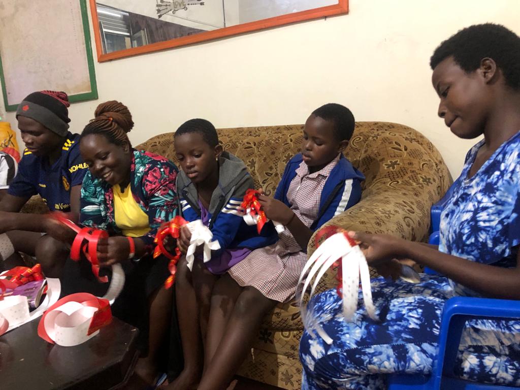 Boys and girls sitting on a couch, helping a woman craft gift bows