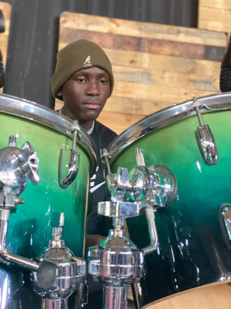A teen boy sits at a drum set